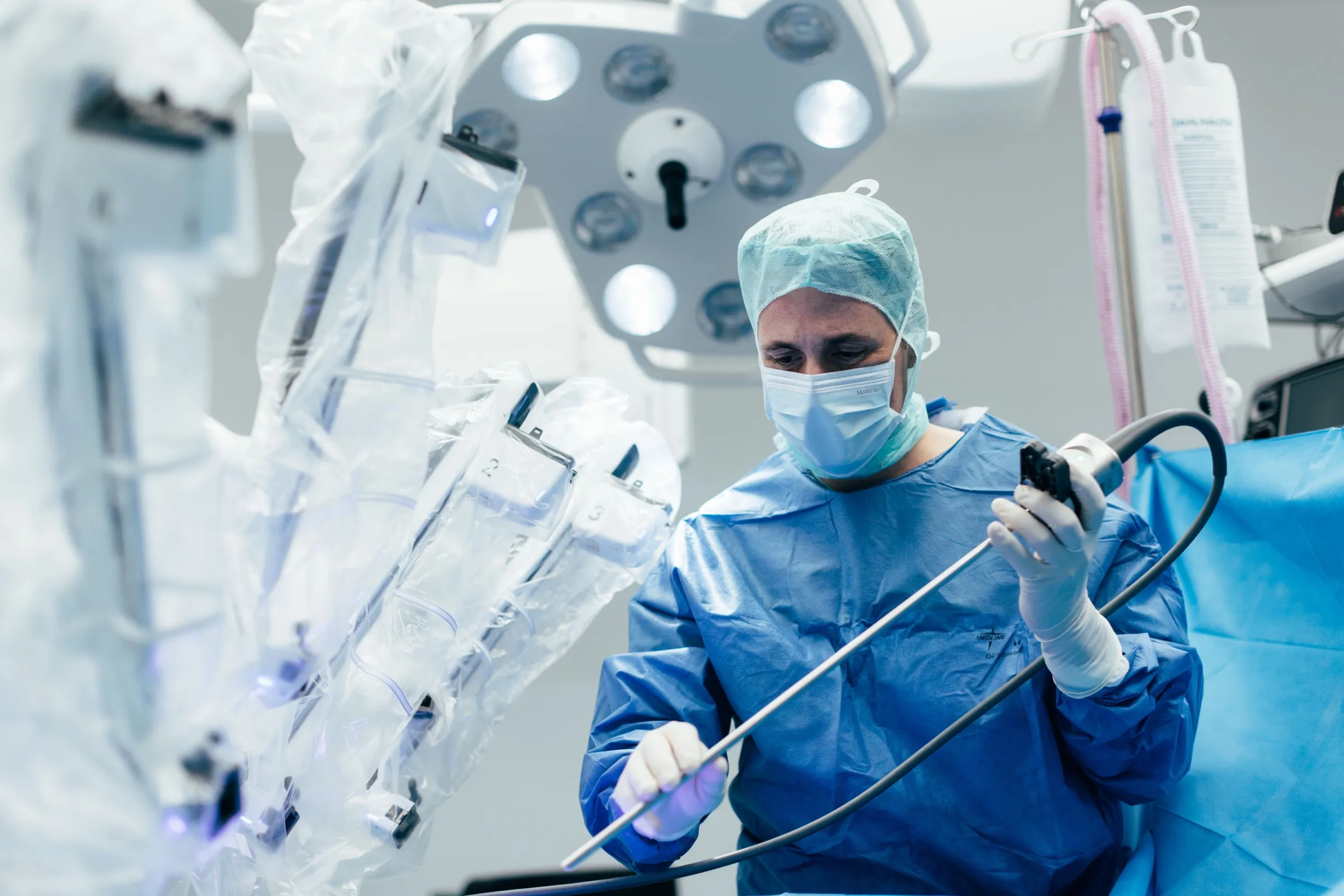 Operateur im sterilen Kittel führt am Operationstisch das Endoskop des da Vinci Systems ein.