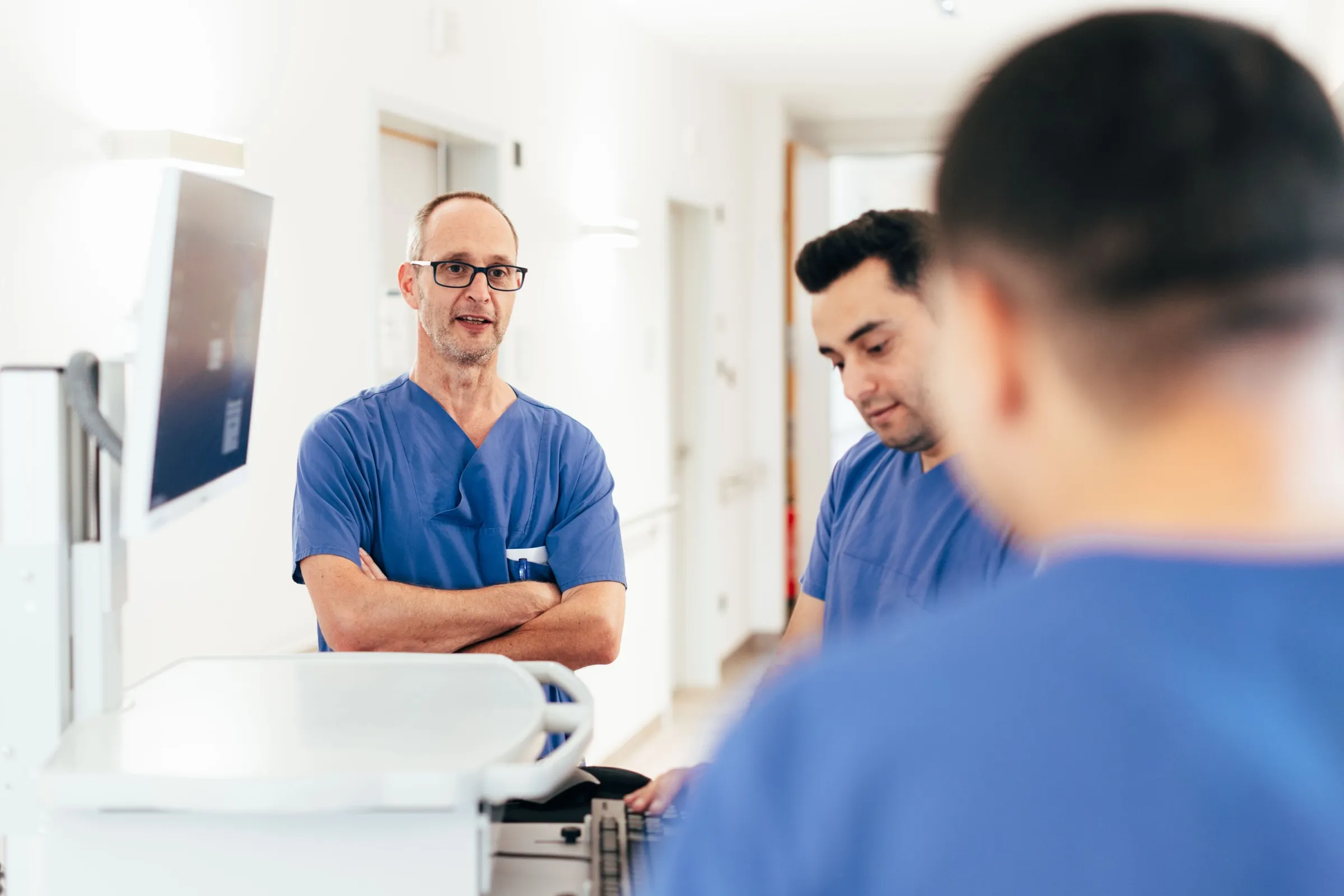Ärzte der Klinik für Urologie besprechen sich auf dem Stationsflur an einem fahrbaren Arbeitsplatz.